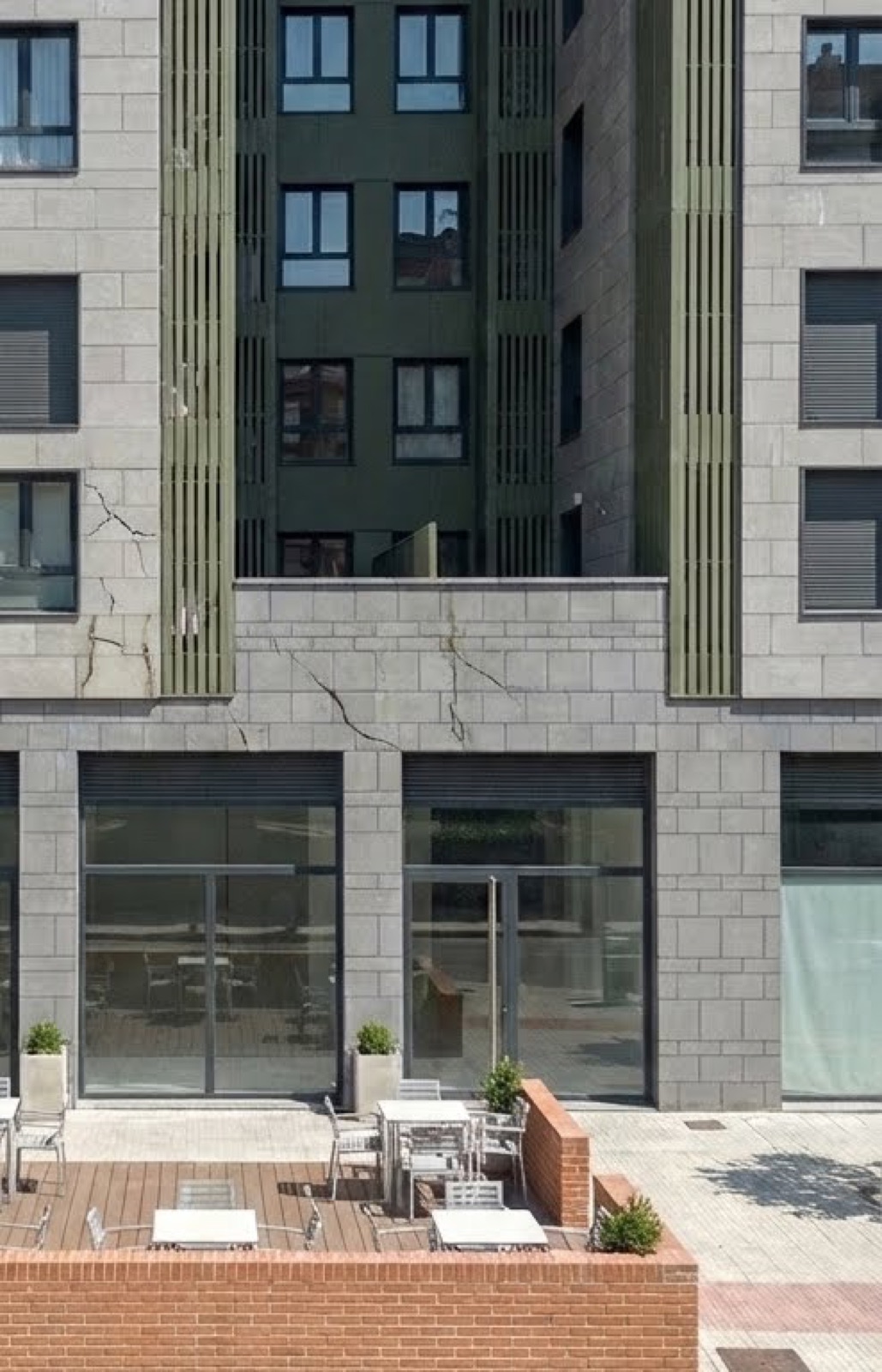 Fisuras múltiples en la fachada de un edificio largo sin juntas de dilatación